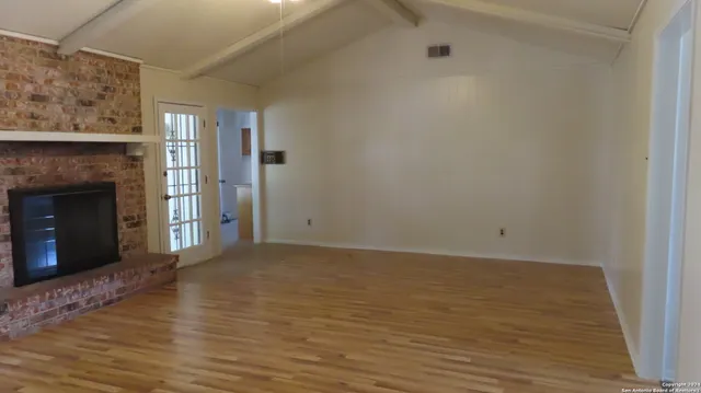 a view of empty room with wooden floor and fireplace