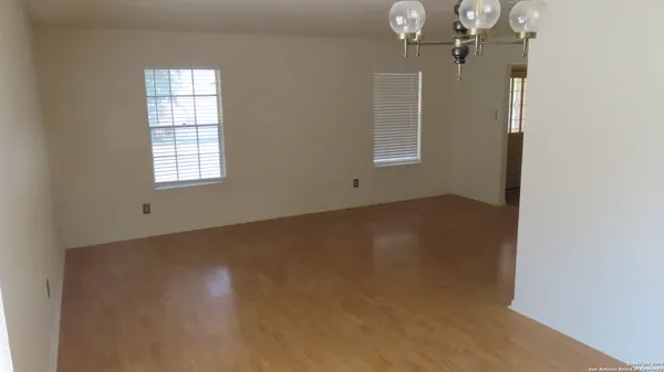an empty room with chandelier fan and windows