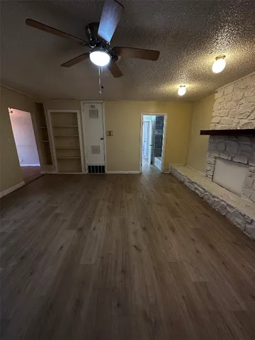 an empty room with wooden floor ceiling fan and window