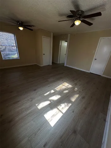 an empty room with wooden floor fan and windows