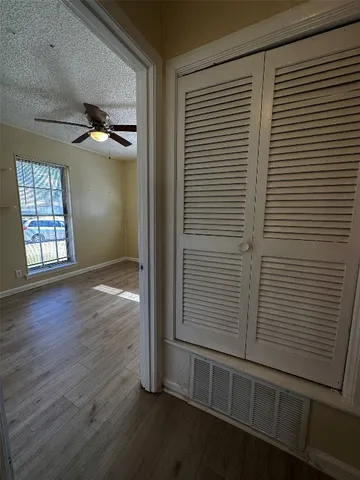 an empty room with wooden floor cabinet and windows