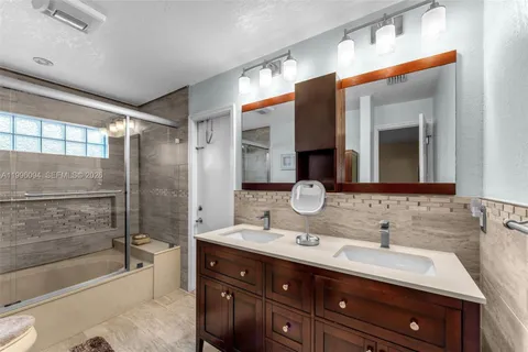 a bathroom with a double vanity sink mirror and bathtub