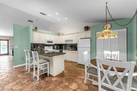 a kitchen with a dining table chairs and cabinets