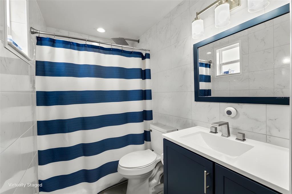 9658 Bayside Court Spring Hill, FL 34608 - Photo 27 of 34 a bathroom with a sink a toilet a mirror and shower curtain