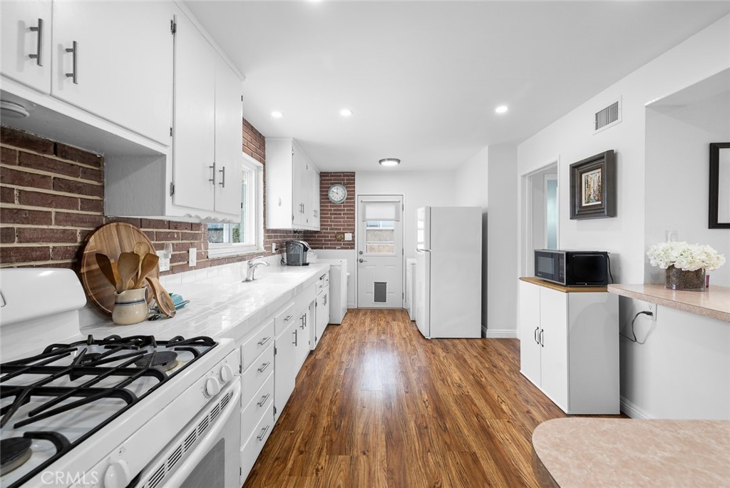 5472 Marion Avenue Cypress, CA 90630 - Photo 10 of 36 a large kitchen with stainless steel appliances a stove a sink dishwasher a refrigerator white cabinets and wooden floor