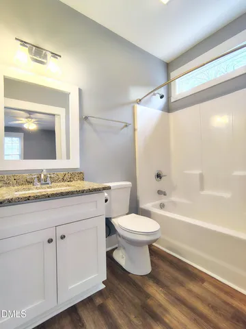 a bathroom with a toilet a sink a mirror a bathtub and vanity