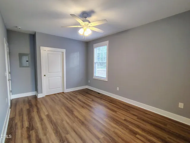 a view of an empty room with window and wooden floor