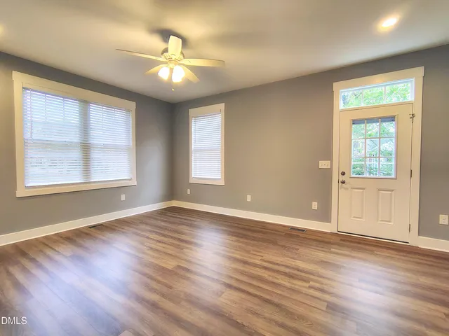 a view of an empty room with wooden floor and a window