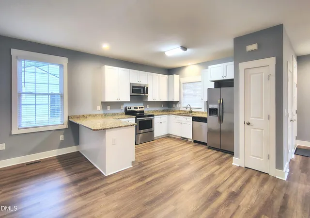 a kitchen with granite countertop a refrigerator stove top oven and sink