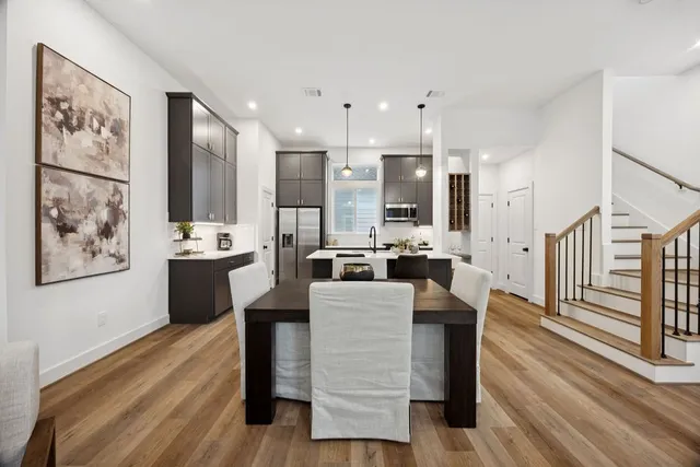 a dining hall with stainless steel appliances kitchen island granite countertop furniture a rug kitchen view and a chandelier