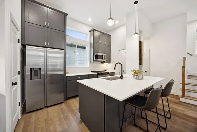 a kitchen with stainless steel appliances granite countertop a sink a microwave a refrigerator and island