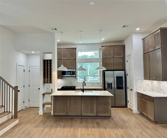 a large kitchen with stainless steel appliances kitchen island granite countertop a large cabinets a sink and a stove