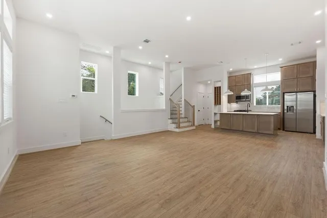an empty room with stainless steel appliances wooden floor and windows