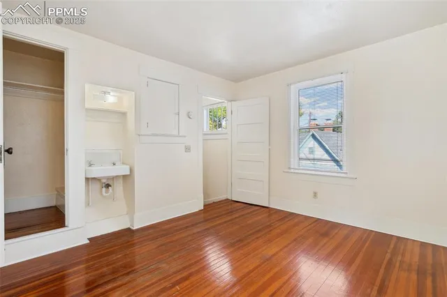 an empty room with wooden floor and windows