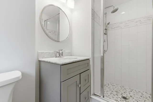 a bathroom with a granite countertop sink a mirror and a shower