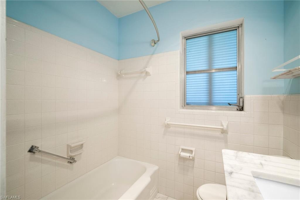 1449 Charles Road Fort Myers, FL 33919 - Photo 18 of 40 Full bathroom featuring vanity, tile walls, tiled shower / bath combo, and toilet