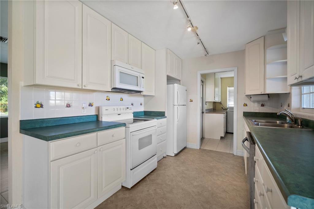 1449 Charles Road Fort Myers, FL 33919 - Photo 26 of 40 Kitchen with white appliances, a wealth of natural light, light tile patterned floors, decorative backsplash, and sink