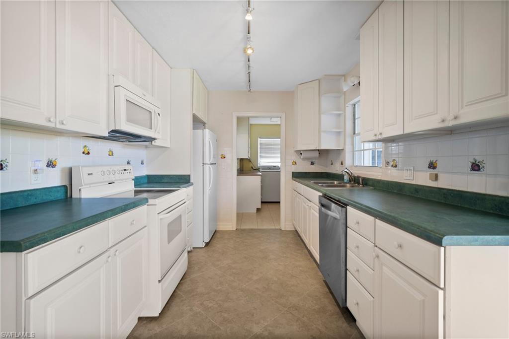 1449 Charles Road Fort Myers, FL 33919 - Photo 27 of 40 Kitchen featuring rail lighting, white appliances, light tile patterned floors, white cabinets, and decorative backsplash