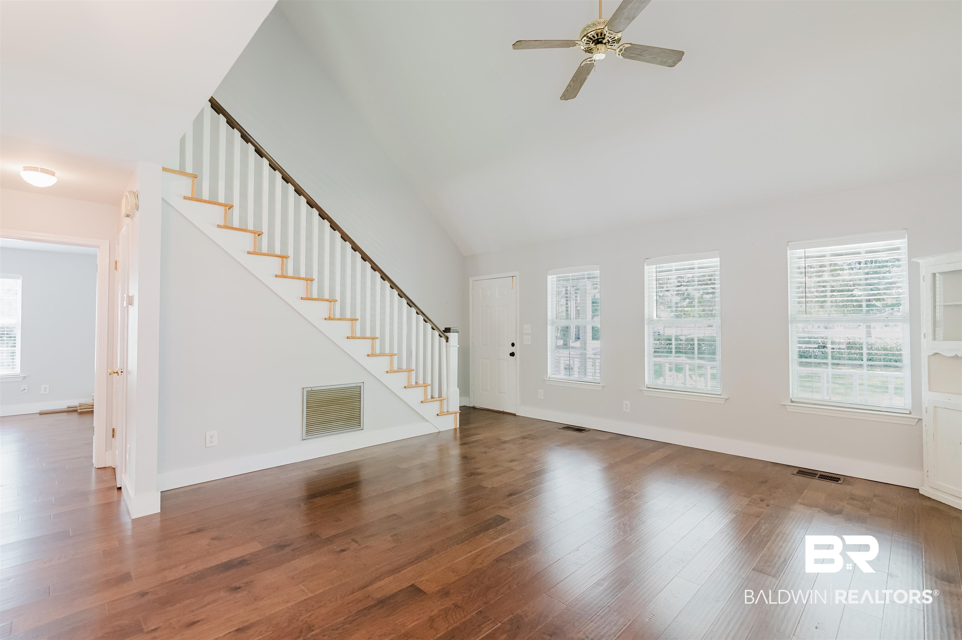 20460 Bishop Road Fairhope, AL 36532 - Photo 10 of 41 Unfurnished living room with stairs, a ceiling fan, wood finished floors, high vaulted ceiling, and baseboards
