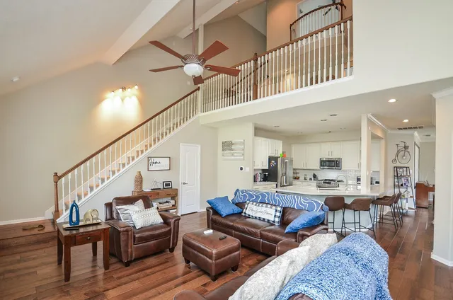 a living room with furniture kitchen view and a wooden floor