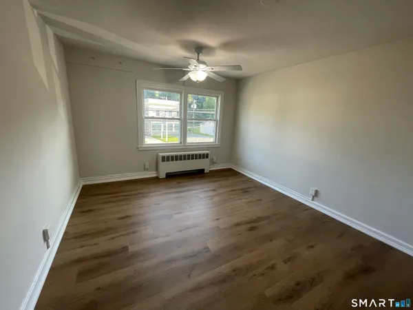 an empty room with wooden floor fan and windows
