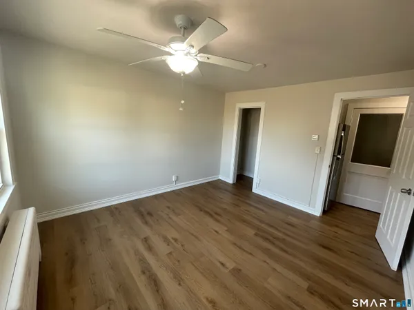 an empty room with wooden floor and fan