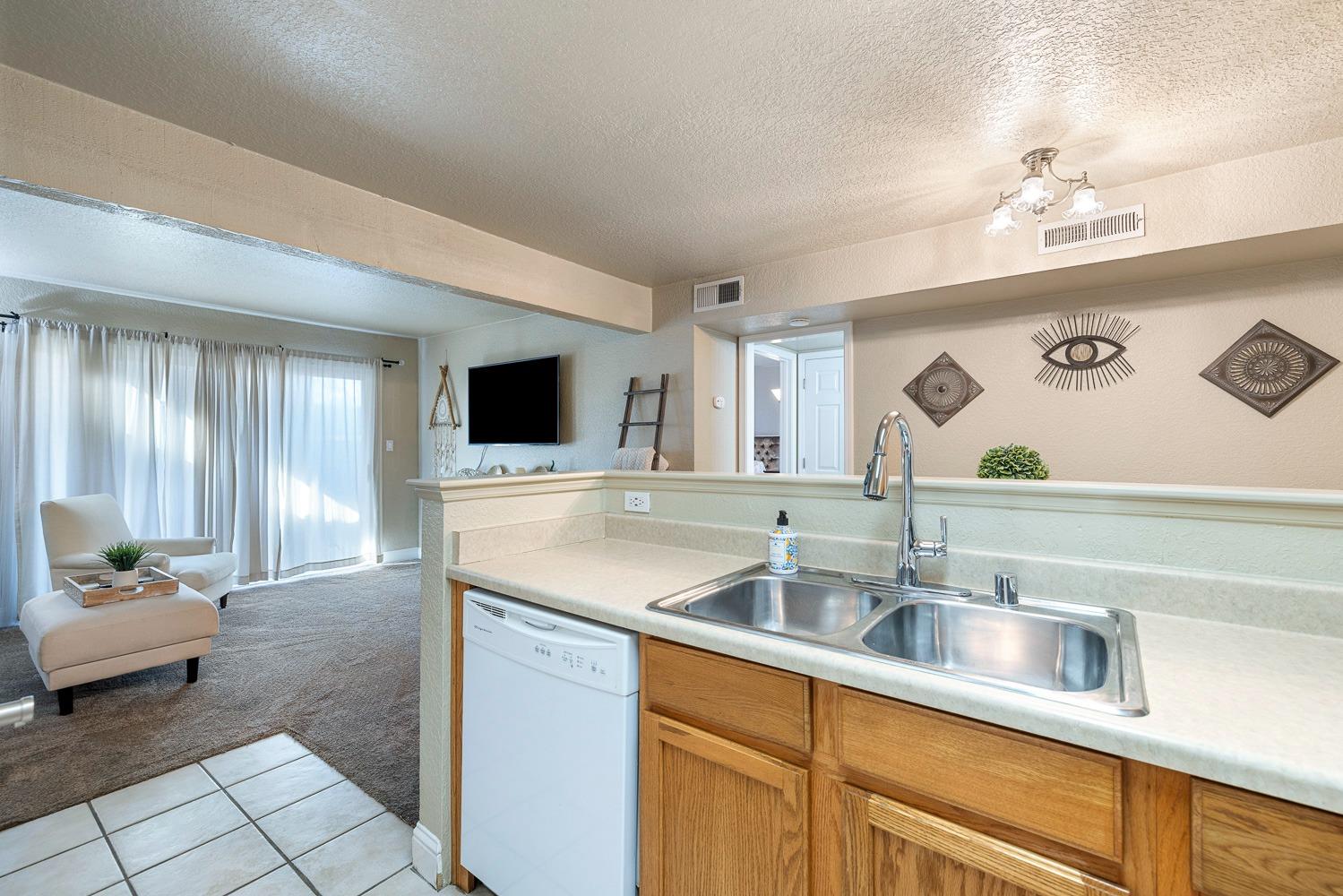 2881 Huntington Boulevard, Unit 137 Fresno, CA 93721 - Photo 9 of 29 a kitchen with a sink dishwasher a stove and a dining table with wooden floor