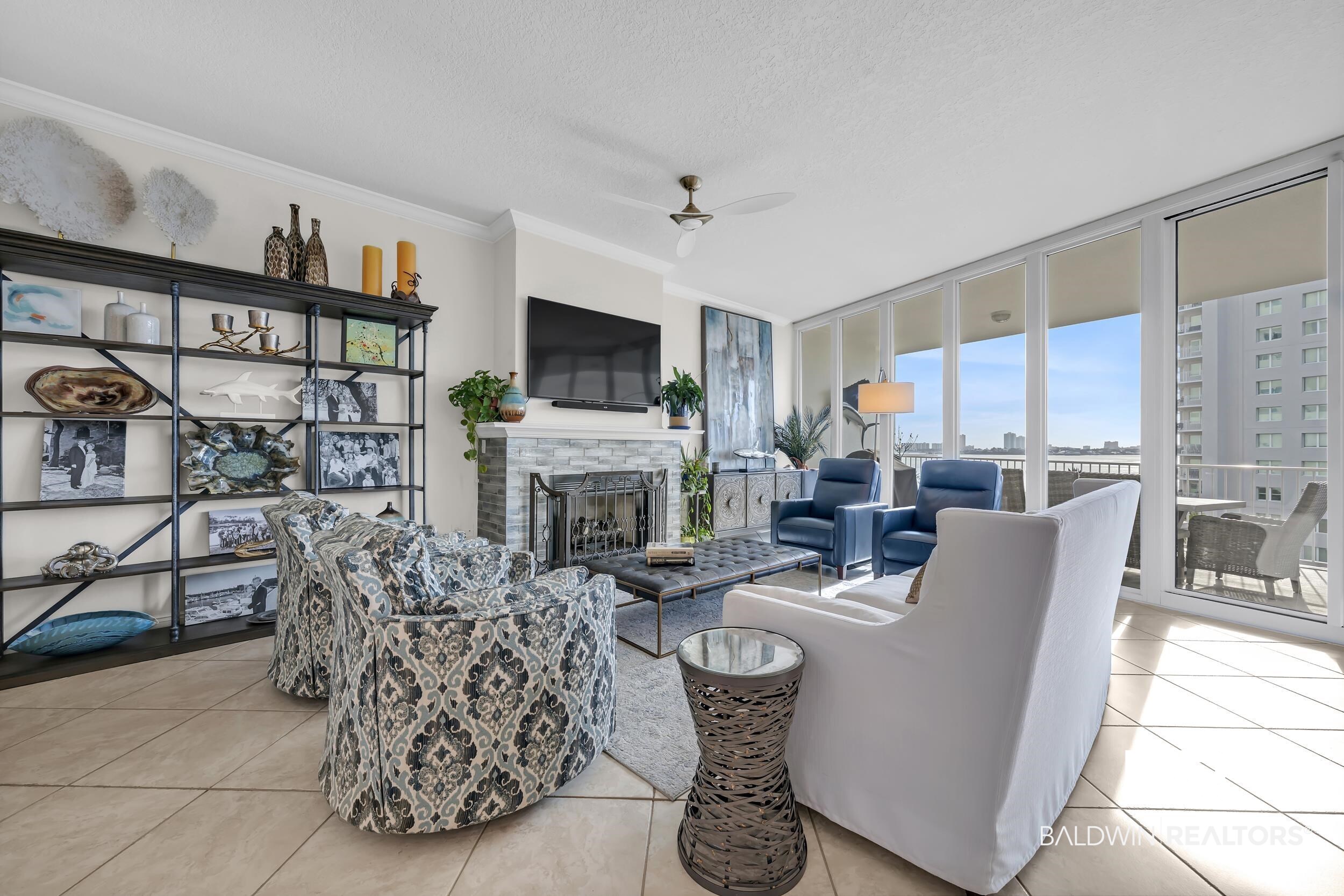 28250 Canal Road, Unit 307 Orange Beach, AL 36561 - Photo 24 of 56 Living room featuring a ceiling fan, a fireplace, light tile patterned floors, ornamental molding, and expansive windows