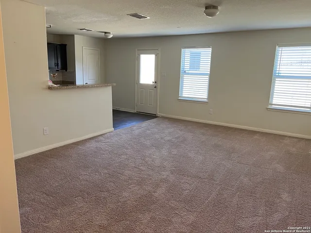 an empty room with windows and fireplace