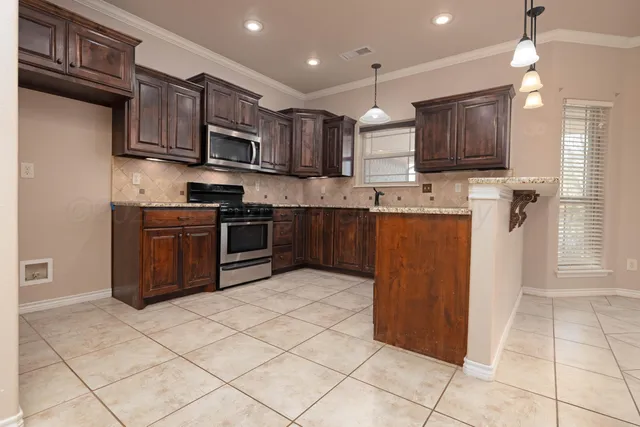 a kitchen with stainless steel appliances granite countertop a stove top oven a sink dishwasher and a refrigerator