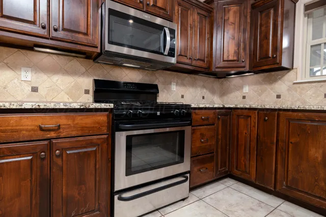 a kitchen with granite countertop wood cabinets and stainless steel appliances