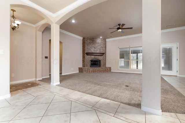 a view of an empty room with chandelier and fireplace