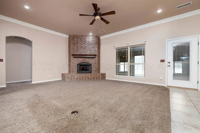 a view of a livingroom with a fireplace a ceiling fan and window