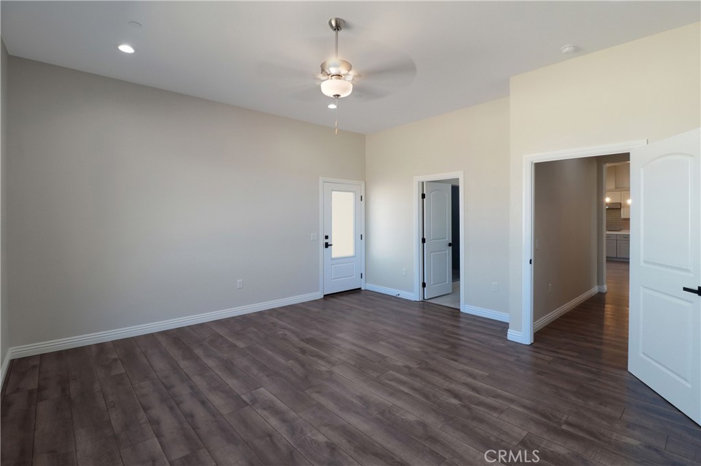 14785 Tigertail Road Apple Valley, CA 92307 - Photo 8 of 20 an empty room with wooden floor chandelier fan and windows