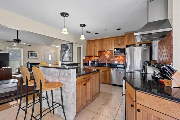 a kitchen with stainless steel appliances granite countertop a refrigerator a sink dishwasher a dining table and chairs with wooden floor