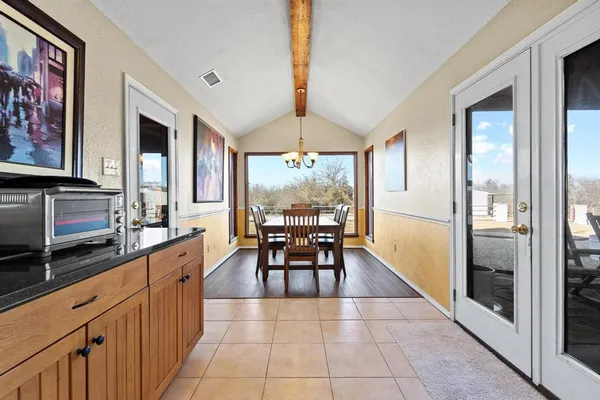 a kitchen with granite countertop a dining table chairs stainless steel appliances and cabinets