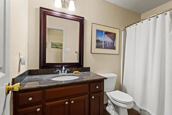 a bathroom with a granite countertop toilet a sink and a mirror
