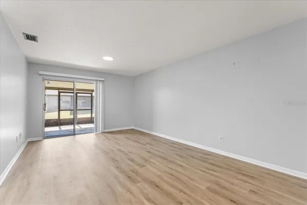 a view of an empty room with wooden floor and window