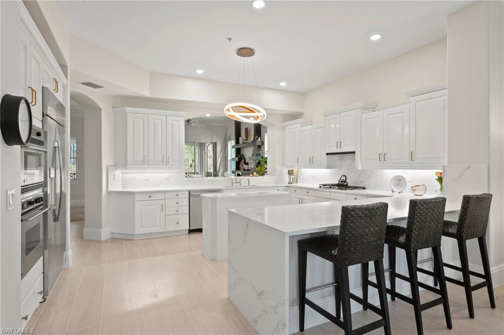 2886 Castillo Court, Unit 103 Naples, FL 34109 - Photo 9 of 38 a kitchen with white cabinets and chairs