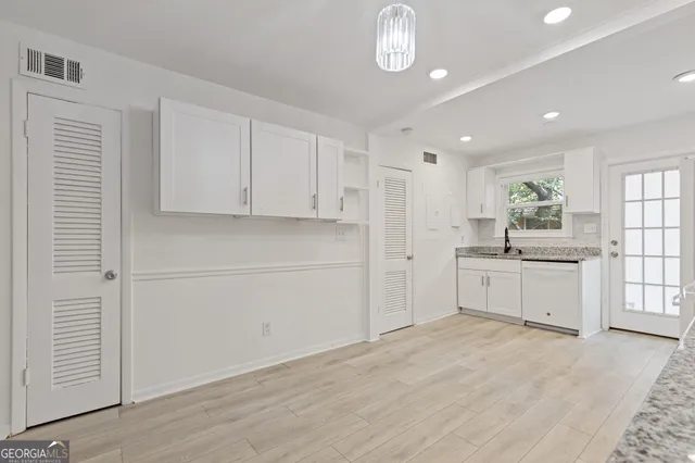 a large white kitchen with window and stainless steel appliances