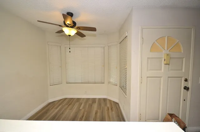 a view of empty room with wooden floor and ceiling fan