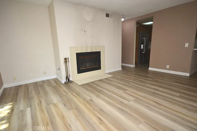 a view of empty room with wooden floor and fireplace