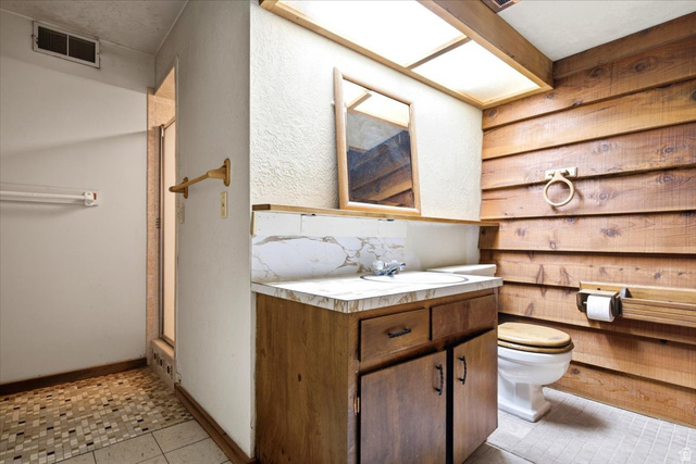 2252 West 800 North Clinton, UT 84015 - Photo 24 of 38 Bathroom featuring a wood-finish vanity with a marbled countertop, an integrated sink, a large mirror, and wood-paneled walls