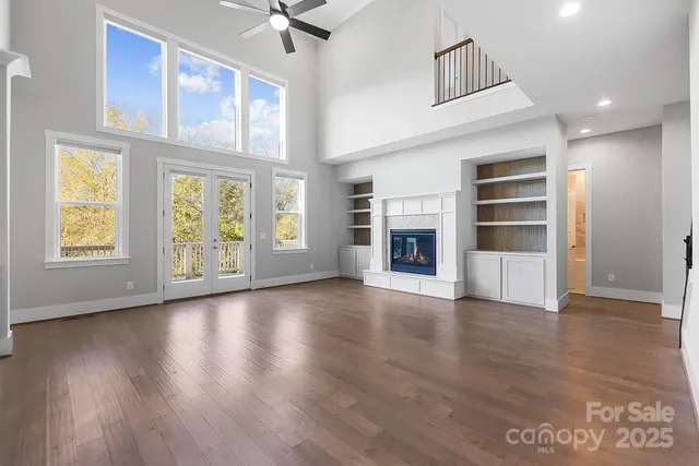 an empty room with wooden floor fireplace and windows