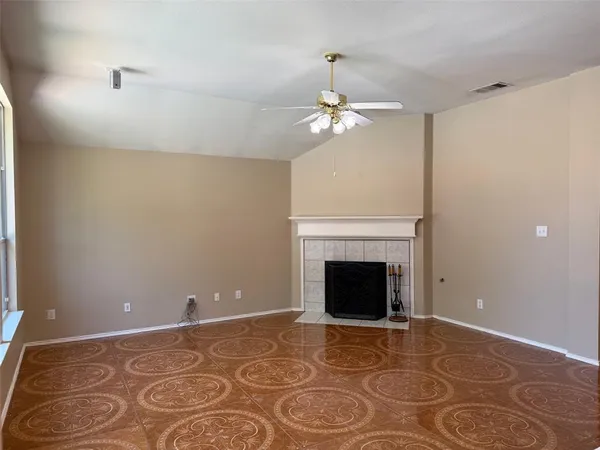 a view of an empty room with a fireplace and a fan