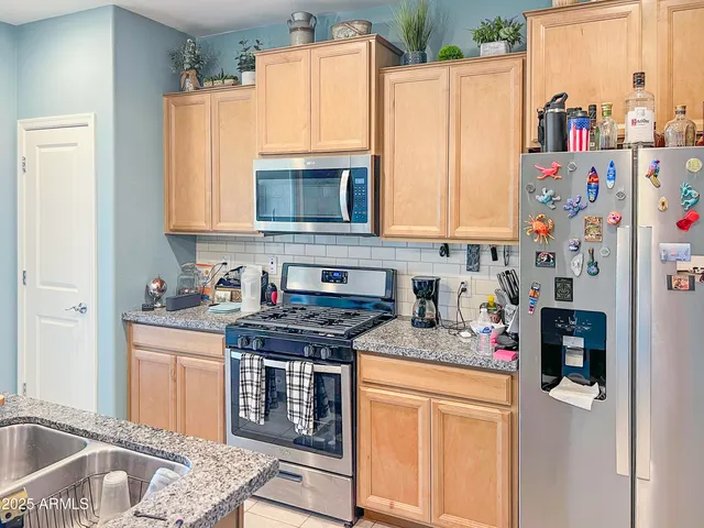 a kitchen with stainless steel appliances granite countertop a stove a sink and a refrigerator