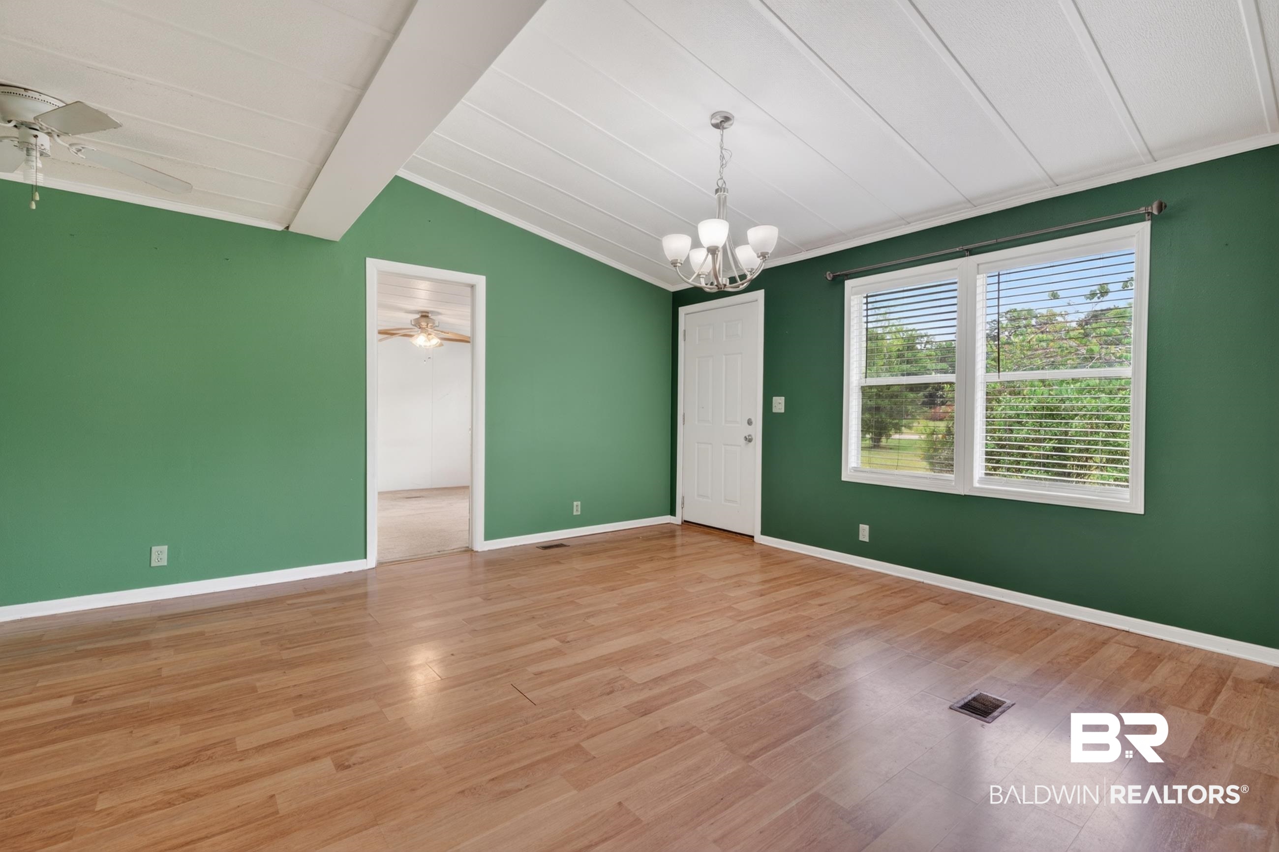 24903 Patterson Road Robertsdale, AL 36567 - Photo 26 of 57 Spacious room featuring wood-finish flooring, vaulted ceilings with exposed beams, and a modern chandelier