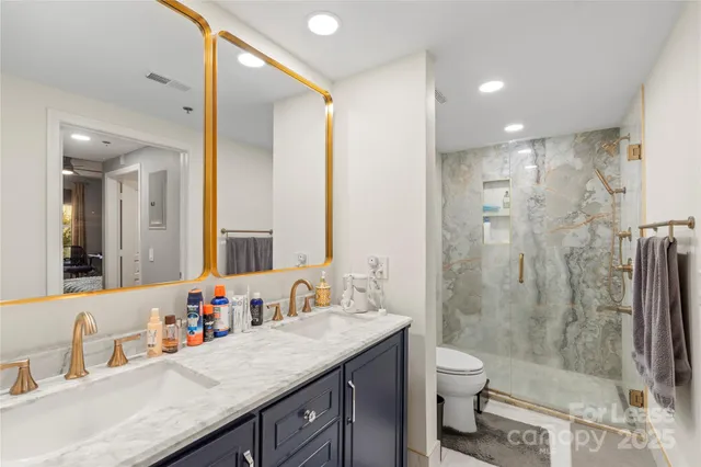 a bathroom with a granite countertop sink a toilet a mirror and shower