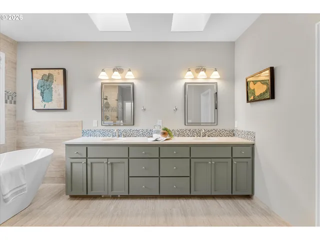 a bathroom with a double vanity sink mirror and bathtub