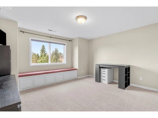 a view of an empty room with a window and a kitchen